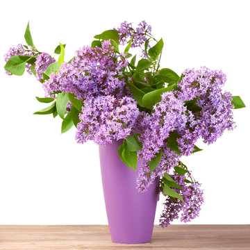 Bouquet of lilac flower in a jug on wooden surface