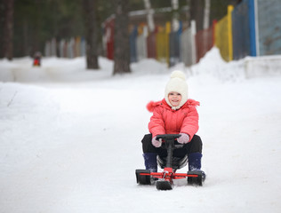 Little boy and girl  slides down from the snow hill on a sledge
