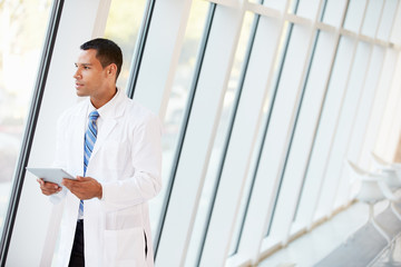 Doctor Using Digital Tablet In Corridor Of Modern Hospital