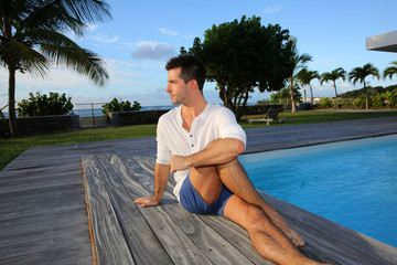 Young man doing stretching exercises on pool deck