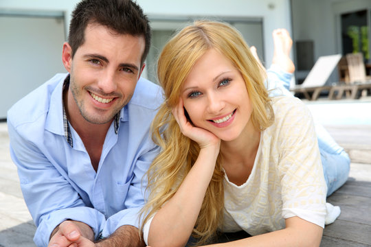 Cheerful young couple sitting in front of modern house