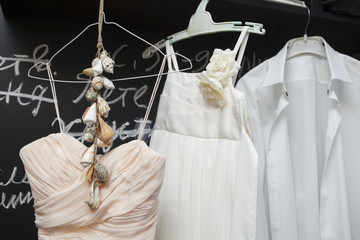 Wedding dress and suit hanging at a wall