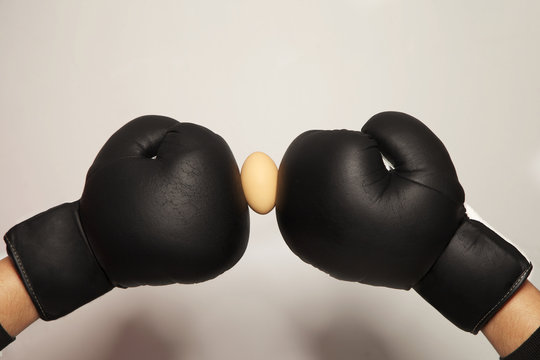Boxhandschuhe in schwarz mit einem rohen Ei