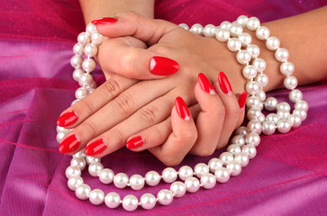 Female hands holding beads on color background