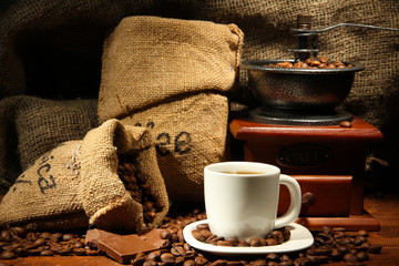 Coffee grinder and cup of coffee on burlap background