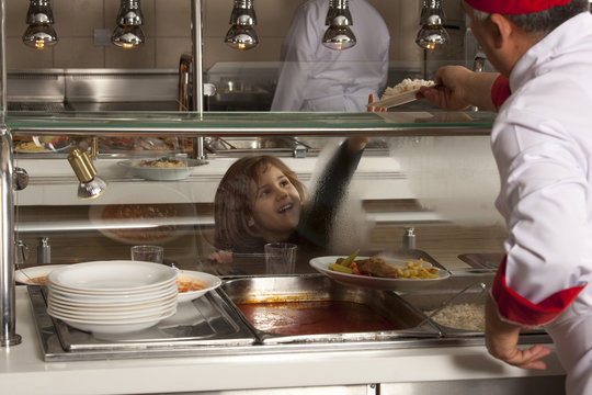 little girl in cafeteria line trying to take her healthy meal