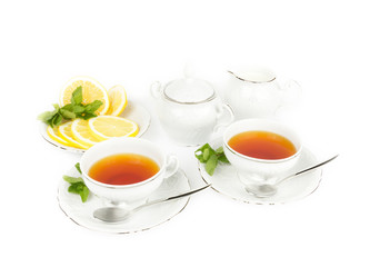 Two cups with tea, teapot, milk and lemon