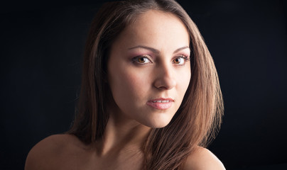 Intense woman close up portrait against dark background.