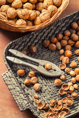 Hazelnuts and walnuts in wicker basket with nut cracker