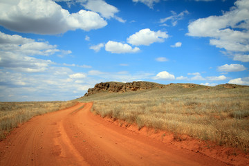 Fototapeta na wymiar Dirt road orange prairie, going to the blue sky