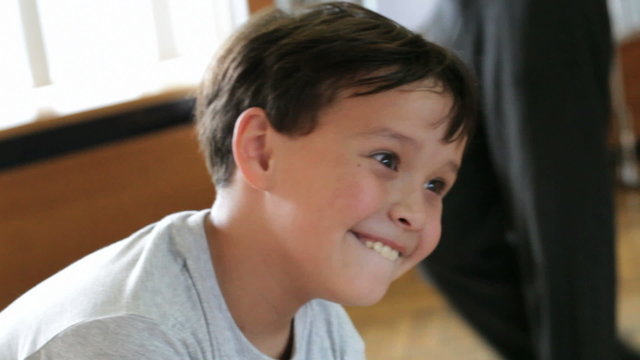 Boy is grimacing in front of the distorting mirror.