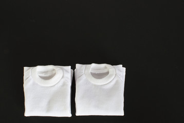 White t-shirts folded on a black background