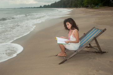 Pretty Thai woman reading a book  on bed beach.