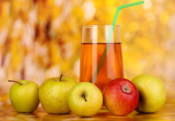 Useful apple juice with apples around on autumn background