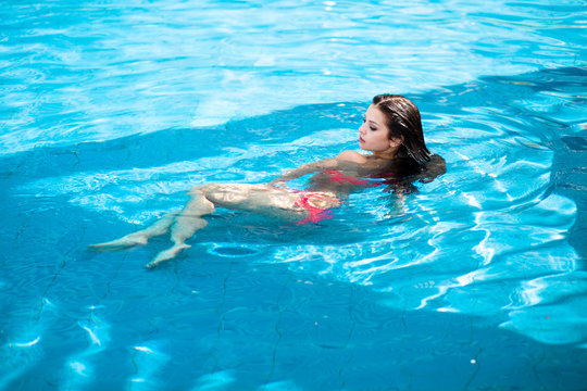 Beautiful woman floating in a swimming pool.