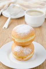 sweet donuts sprinkled with powdered sugar and a cup of coffee