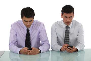 Businessmen sending text messages simultaneously