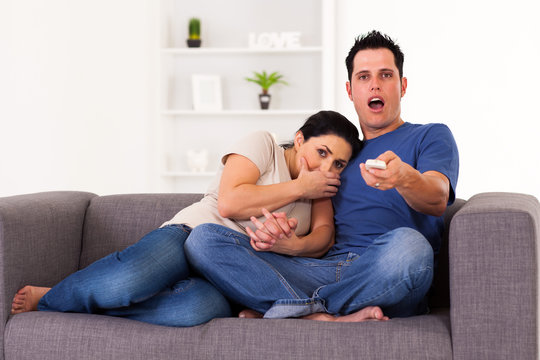 Young Couple Watching Scary Horror Movie At Home