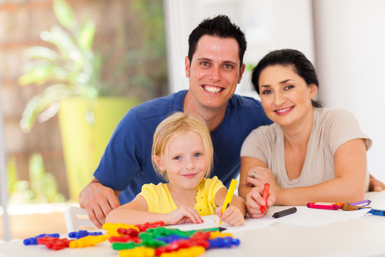happy parents and little daughter drawing pictures at home