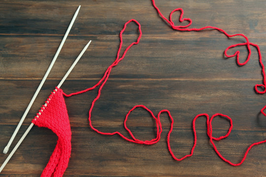 Knitting yarn with word Love on wooden background