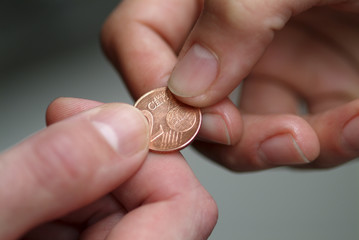 Hand giving 2 cents euro coin to other hand.