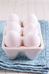 Six fresh eggs in egg holder on blue napkin