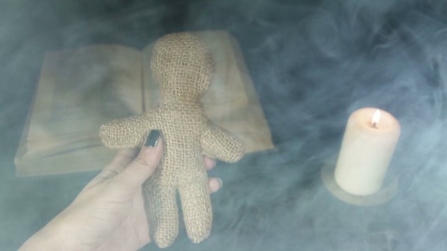 Witch voodoo doll with a pin pierces in the smoke