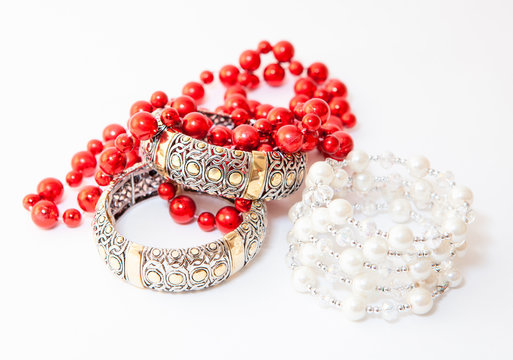 Two white gold braceletes and red necklace on white background