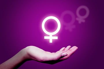 Shining female sex sign, woman's hand on violet background