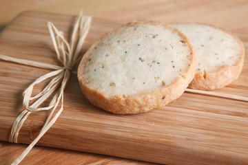 Two crisp anise cookies on wooden cutting board