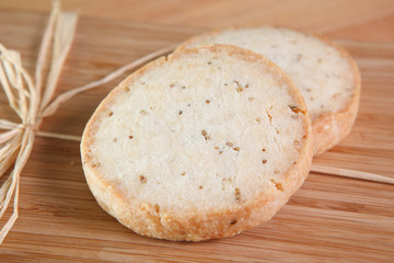 Two crisp anise cookies on wooden cutting board