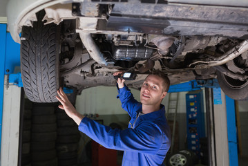 Mechanic with flashlight under car