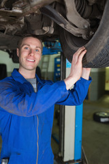Happy mechanic examining car tire