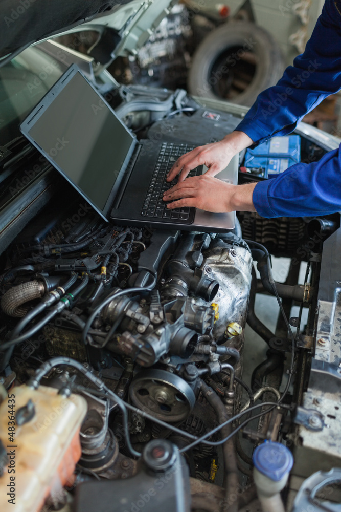 Poster mechanic hands using laptop on car engine