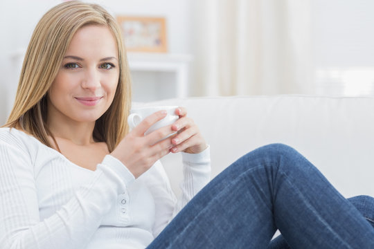 Woman with coffee cup sitting on couch