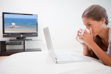 Woman taking a sip of coffee while surfing the internet in the l