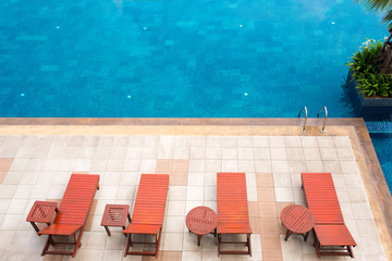 poolside deckchairs alongside blue swimming pool