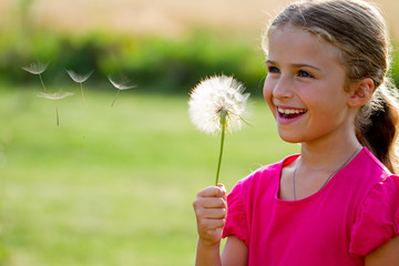 Allergy season - lovely girl blowing dandelion