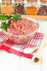 Bowl of raw ground meat with spices on wooden table