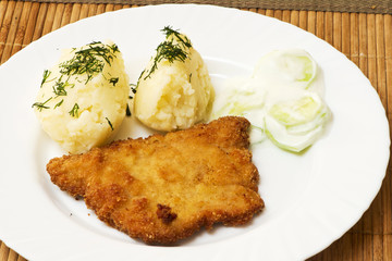 potatoes, pork chop and salad with cucumbers and cream