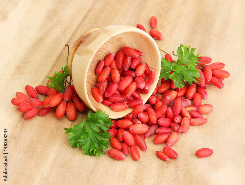 Canvas Prints ripe barberries in wooden bowl with green leaves, on table