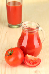 Full jug of tomato juice, on wooden background