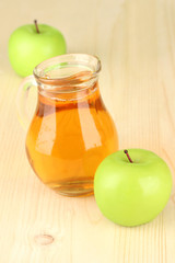 Full jug of apple juice and apple on wooden background