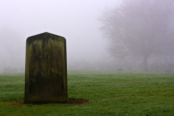 Single gravestone in a spooky graveyard on a foggy day