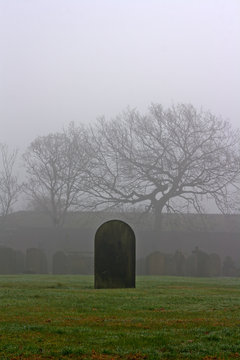 Single gravestone in a spooky graveyard on a foggy day
