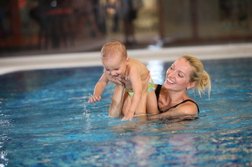Fototapeta na wymiar Young mother and little son having fun in a swimming pool