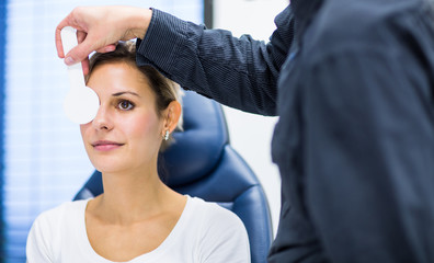 Optometry concept - pretty young woman having her eyes examined