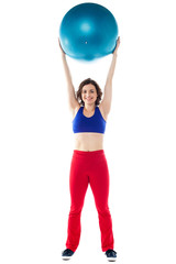 Happy woman lifting pilates ball upwards