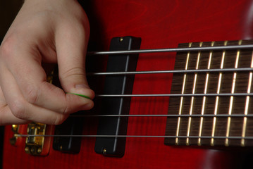 Playing on bass guitar with red body