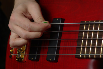 Playing on bass guitar wuth red body